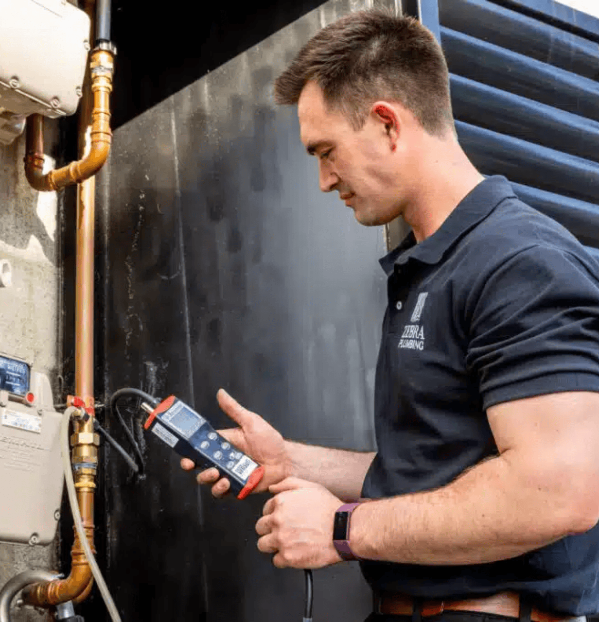 Zebra Plumbing technician testing a gas meter with a digital manometer.