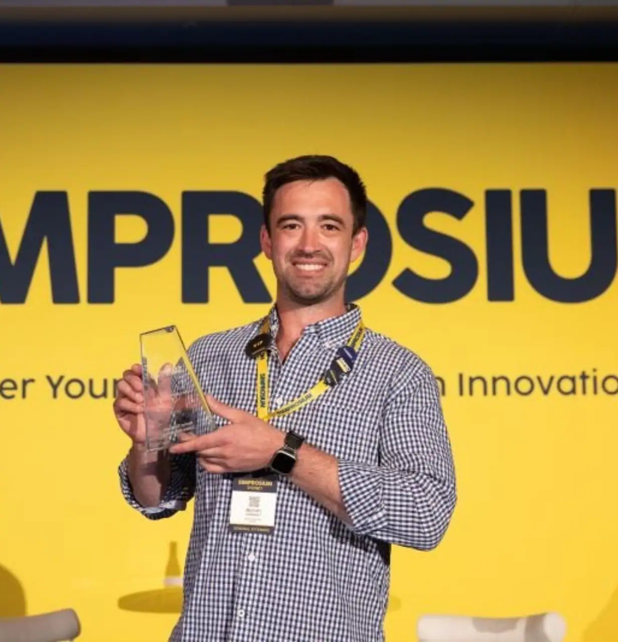 Man holding an award at ProSiu event with yellow background.